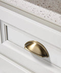 Premium Upgraded Top Shelf 3 Inch Brushed Antique Brass Cabinet Cup Pulls on white kitchen drawer with countertop visible.
