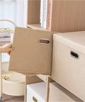 Heavy Duty Fabric Storage Bins With Snap On Lids Stackable Khaki Storage Boxes textured cover being pulled from shelf.