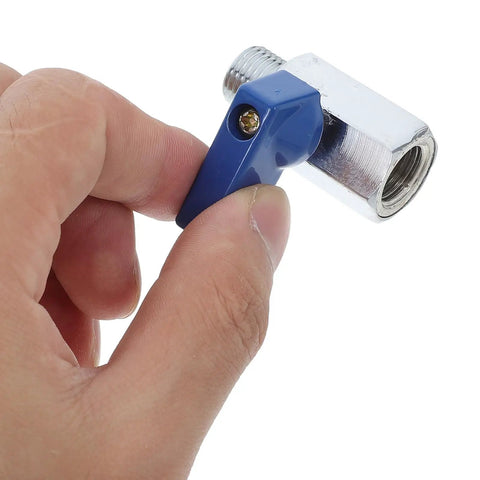 Slick Brass Mini Ball Valve With Npt One Quarter Inch Threaded Ends Designed For Tight Squeeze Spaces And Delivering Heavy Duty Plumbing Performance Without Any Drama Or Hassle being held, showcasing blue lever and threaded end.