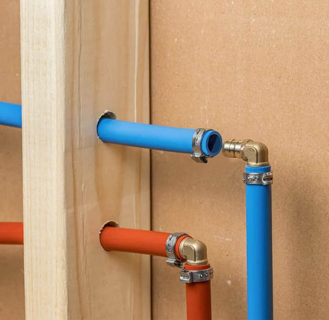 10 Pack Brass PEX Elbow Fittings One Half Inch 90 Degree For PEX Tubing Durable Potable Water Approved SDWA 2014 Compliant Plumbing Connectors Set Perfect For Home Renovation And New Installations In Indoor Or Outdoor Plumbing Projects, installed in blue and red PEX tubing in wall setup.
