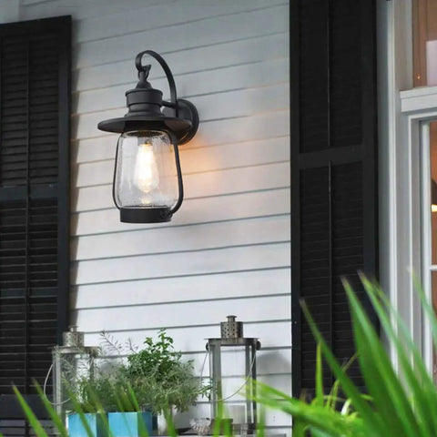 Rock Solid Outdoor Wall Lantern With Slick Industrial Design And Transparent Bubble Glass Shade Featuring A Top Shelf Led Filament Bulb illuminating porch.