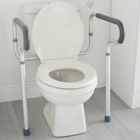 Adjustable Toilet Safety Frame And Rail With Padded Waterfall Armrests Gives You Straight Up Stable Balance As A No Fuss Heavy Duty Bathroom Assist Handle For Seniors next to a white toilet.