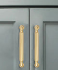 Brushed gold cabinet pulls mounted on gray cabinet doors, showcasing 10 Pack 5 Inch Hole Center Brushed Gold Cabinet Pulls Rock Solid Heavy Duty Drawer Handles Rust Proof Matte Satin Kitchen Bathroom Vanity Dresser Hardware Smooth Operation Hassle Free Setup.