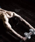 Man using Rock Solid Ab Core Roller Wheel With Thick Foam Handles And Memory Foam Knee Pad on dark floor for intense fitness training.
