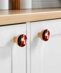 Dope Abstract Red And Black Cabinet Knobs Set 1.4 Inch Solid Beech Wood Drawer Pulls featuring two knobs on a kitchen cabinet.