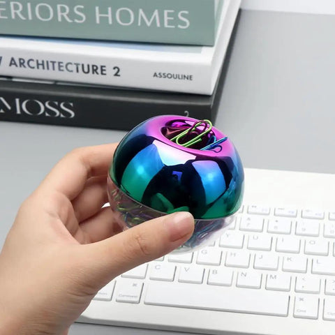 Hand holding Colorful Paper Clips Holder and Dispenser Set with holographic rainbow clips, 28mm paperclips, on keyboard