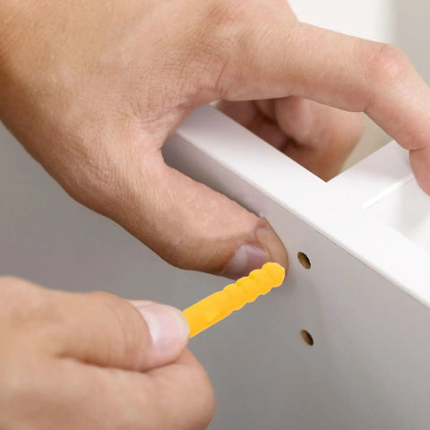 Hand inserting yellow plug from Yellow Plastic Wall Plugs Kit With Self Drilling Anchors 200 Piece Set For Hollow Walls Plasterboard.