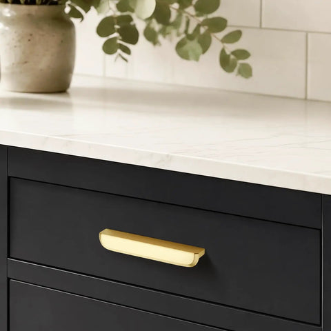 Heavy Duty Thirty Pack Cabinet Pulls And Kitchen Drawer Handles Cast In Rich Brushed Brass With A Precise Five Inch Spread showcased on a black drawer.