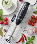 Boost Your Meal Prep Hustle With This Badass 500W Immersion Hand Blender showing black grip, stainless shaft, and kitchen ingredients.
