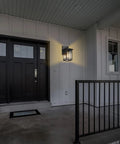 Dusk To Dawn Exterior Wall Lights With Built In Sensor illuminated on porch, showing black door and railing, 1 of 2 pack sconces.