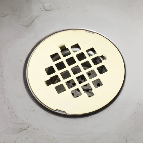 Rock Solid Gold Snap In Shower Drain Cover For Four Quarter Inch Round Stainless Steel Strainer on bathroom floor.