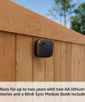 Guard Your Property With Zero Hassle Using This Five Camera Wirefree Home Security Kit That Delivers Hella Sharp 2K Doorbell Footage Quick Sync Module Hookup And Two Year Battery Life Modern Black mounted camera on a wooden fence.