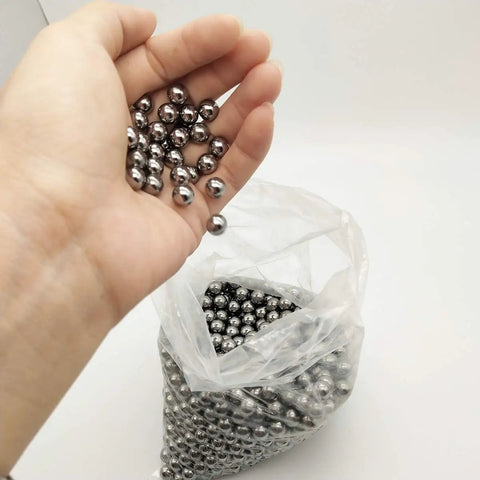 Hand holding Top Tier G1000 Carbon Steel Round Balls, showing precision metal shot for slingshot ammo.