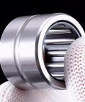 Top Shelf Machined Needle Roller Bearing Set With Heavy Duty Outer Ring Flanges And Tight Guided Cages held in hand, showcasing precision engineering.