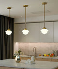 Elegant kitchen with three brass pendant lights hanging over island