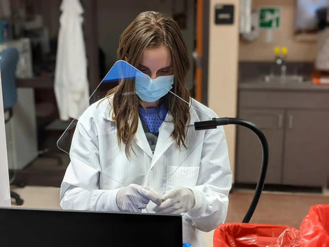 Person using Heavy-Duty Flexible Arm Safety Shield With Magnetic Base, 18-Inch Reach, 10x10 Inch Shield, in lab setting.