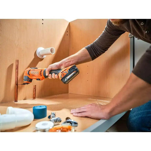 Person using 18V Cordless Oscillating Multi Tool Kit With Two 2.0Ah Batteries And Charger to cut under-sink pipes