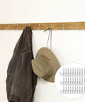 Thirty Pack Mini Iron Wall Hooks With Classic Silver Finish holding a jacket and hat on a wooden wall mount.