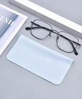 Two items: light-blue 230GSM microfiber eyeglass cleaning cloth and black-framed glasses.