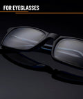 Side view of black plastic eyeglasses with clear lenses on a dark surface