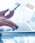 Person using laptop while holding smartphone, showcasing multitasking in a modern workspace with a clean design.
