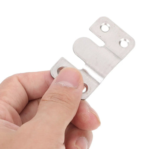 Hand holding a stainless steel interlocking clip from the Six Pair Heavy Duty Picture Frame Hangers for secure wall mounting.