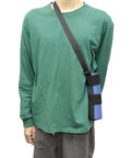 Person wearing green shirt with blue cylindrical item in black strap sling