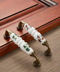 10 Pack Vintage Ceramic Cabinet Pulls Featuring Hella Charming Red Floral Motifs On Creamy White Porcelain Base Coupled With Antique Bronze Zinc Alloy Hardware For Authentic French Country Kitchen Cabinets Drawers And Furniture 96mm Hole Centers, displayed on wood.