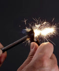 Close-up of hands using 2 Pack Compact Fire Starters With Scraper Striker igniting sparks in dark background.