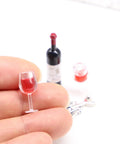 Hella Cool Miniature Red Wine Bottle Set Featuring Two Resin Filled Wine Glasses And A Static Corkscrew For Dollhouse Decor, hand holding a resin glass.