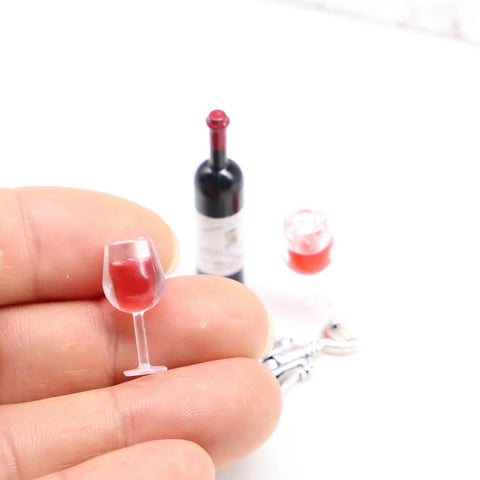 Hella Cool Miniature Red Wine Bottle Set Featuring Two Resin Filled Wine Glasses And A Static Corkscrew For Dollhouse Decor, hand holding a resin glass.