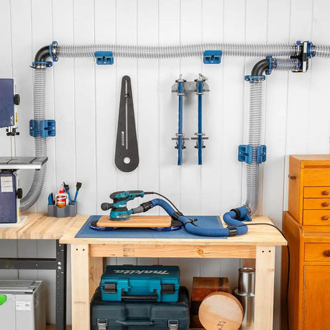 Premium Rockler Dust Right 4 Inch Hose Cradles mounted to workshop wall, supporting dust hoses and tools for ventilation.