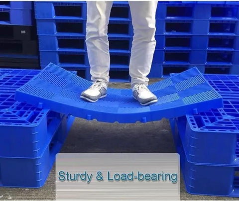 Person standing on blue interlocking plastic pallet with ventilated grid design waterproof moisture proof heavy duty storage pad