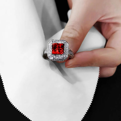 Front view of a silver-tone ring with a square red center gemstone, surrounded by a halo of small crystals.
