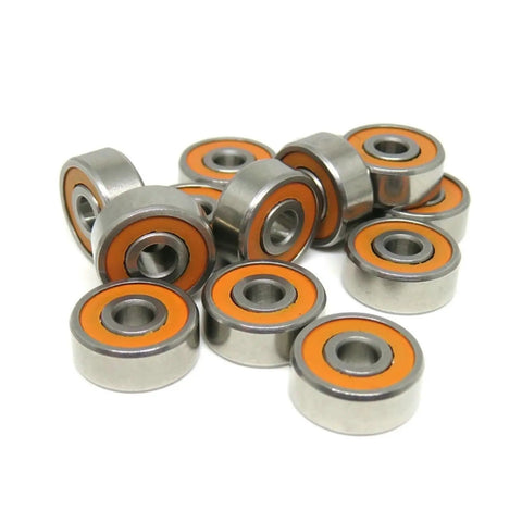 Close-up of Kickass S623C Hybrid Ceramic Ball Bearings 3X10X4MM in a pile, showcasing stainless steel and orange rubber seals.
