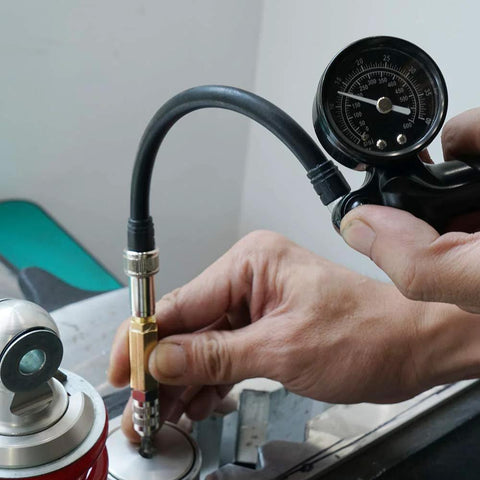 Close-up of NICECNC nitrogen needle kit with needle head replacement connected to a shock absorber; gauge and hose visible.