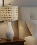 Nightstand with transitional drum lamp shade, spider construction, beige faux linen fabric, gold print, 12 inch wide brass fitter.