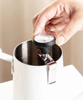 Close-up of Pro Grade Milk Frothing Pitcher With Precision Pour Spout 21 Ounce Steaming Jug With Thermometer Pen, stainless steel.