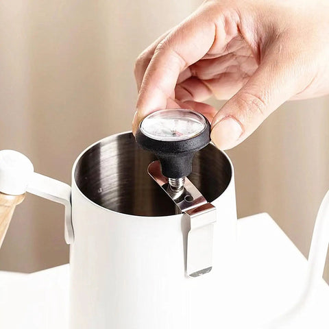 Close-up of Pro Grade Milk Frothing Pitcher With Precision Pour Spout 21 Ounce Steaming Jug With Thermometer Pen, stainless steel.