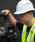 Top Tier Semi Frame Safety Glasses With Clear Lens pack on worker inspecting machinery wearing a hard hat and high-visibility vest.