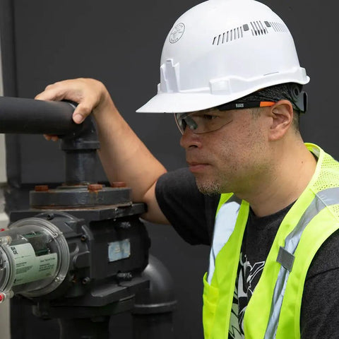 Top Tier Semi Frame Safety Glasses With Clear Lens pack on worker inspecting machinery wearing a hard hat and high-visibility vest.