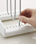 Hand adjusting gray wire divider on white adjustable extra wire pan and lid rack dividers for kitchen organization.