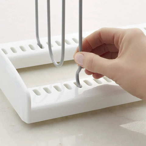 Hand adjusting gray wire divider on white adjustable extra wire pan and lid rack dividers for kitchen organization.