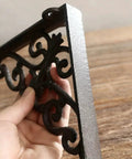 Slick Vintage Black Shelf Brackets Rock Solid Cast Iron L Brackets With Timeless European Scroll Detail shown in hand.