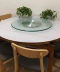 Hella Smooth Tempered Glass Lazy Susan Heavy Duty Turntable Revolving Serving Tray on a round dining table with plants.