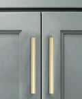 Close-up of Heavy Hitter Brushed Gold Cabinet Pulls 10 Pack Solid Drawer Hardware 6 Inch Hole Center on gray cabinet doors.