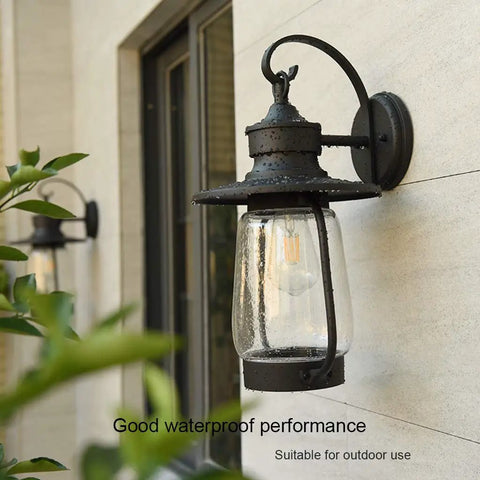 Rock Solid Outdoor Wall Lantern With Slick Industrial Design And Transparent Bubble Glass Shade Featuring A Top Shelf Led Filament Bulb For Sweet Porch Lighting And Dreamy Patio Vibes In Heavy Duty Black Coating mounted on outdoor wall with clear glass.