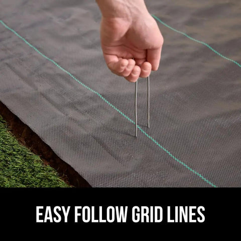 Hand securing Heavy Duty Weed Barrier Fabric 4 Ft By 50 Ft Durable Woven Ground Cover For Driveways, Garden Beds, And Landscaping