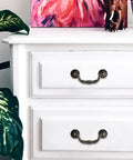 Straight Up Vintage Antique Bronze Drop Bail Pulls With Slick Carved Texture on white drawer fronts with plants.