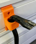Heavy Duty Garage Hooks That Fit Track Panels holding a black tool on orange metal hanger mounted on a wall.